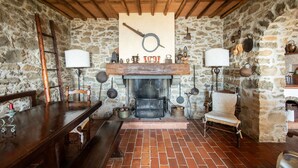 A rustic stone-walled room with a wooden ceiling, a fireplace, and traditional furnishings including a bench, table, and a chair. - Villa Iris with Swimming Pool (Capannori)