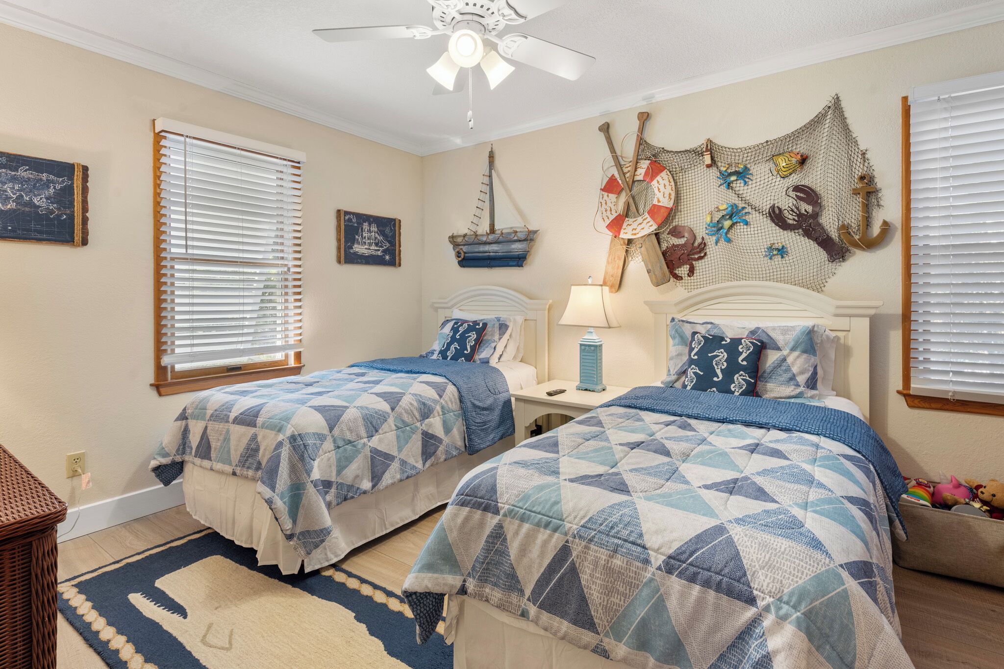 Une chambre avec deux lits, une décoration sur le thème de la marine et un tableau représentant un navire au mur.