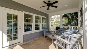 A covered porch with a ceiling fan, a seating area with striped cushions, and a view of the outdoors. - 40 N. Forest Beach-New Owners & Vrbo listing - 176 Yard walk to the beach. (Hilton Head Island)