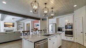 A modern kitchen with white cabinetry, stainless steel appliances, and a marble countertop. - 40 N. Forest Beach-New Owners & Vrbo listing - 176 Yard walk to the beach. (Hilton Head Island)