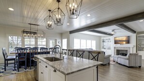 A spacious kitchen with a large island, modern pendant lights, and a dining area with chairs. - 40 N. Forest Beach-New Owners & Vrbo listing - 176 Yard walk to the beach. (Hilton Head Island)