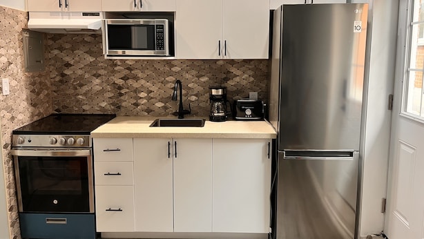 A compact kitchen with a stove, microwave, refrigerator, and coffee maker. - One bedroom apartment/suite  (Whitby)