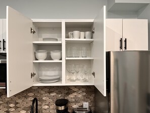 A kitchen with white cabinets, a stainless steel refrigerator, and a coffee maker on the counter.