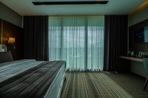 A hotel room with a large bed, a desk with a chair, a television, and a window with curtains. - B'İstanbul Hotel (Istanbul)