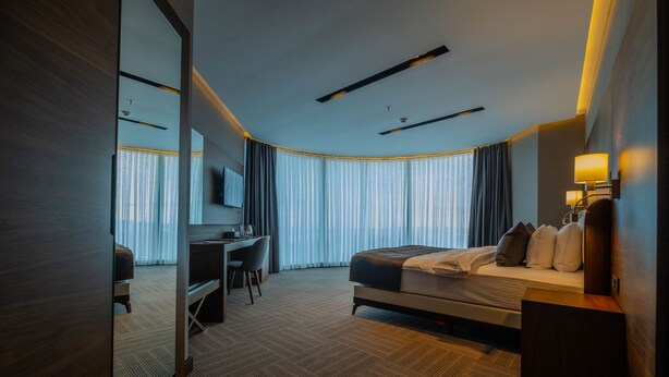 Una habitación de hotel moderna con una cama grande, un escritorio y un televisor.