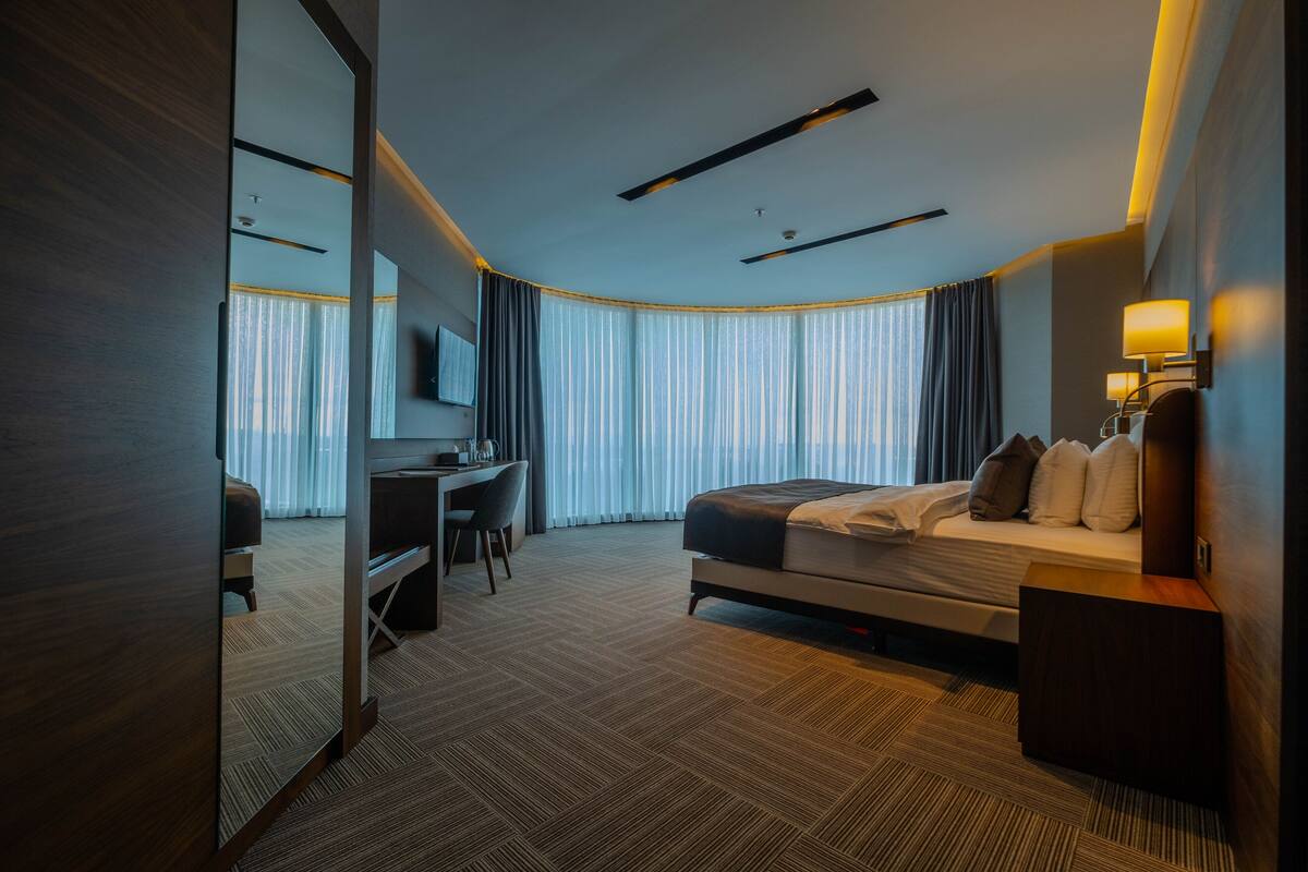 A modern hotel room with a large bed, a desk, and a TV.