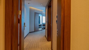 Un pasillo de hotel con puertas de madera, suelo alfombrado y una cama al fondo.