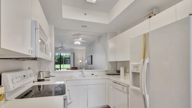 A modern kitchen with white cabinetry, a built-in oven, a dishwasher, and a refrigerator. - Cypress Woods for Seasonal or Summer Stays W Golf (Naples)