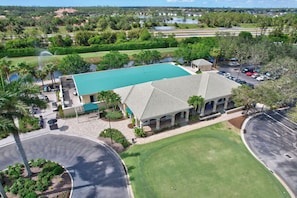 A building with a green roof, surrounded by a parking lot and a golf course.