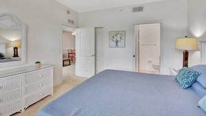 A bedroom with a large bed, a dresser, a mirror, and a door leading to a bathroom. - Cypress Woods for Seasonal or Summer Stays W Golf (Naples)