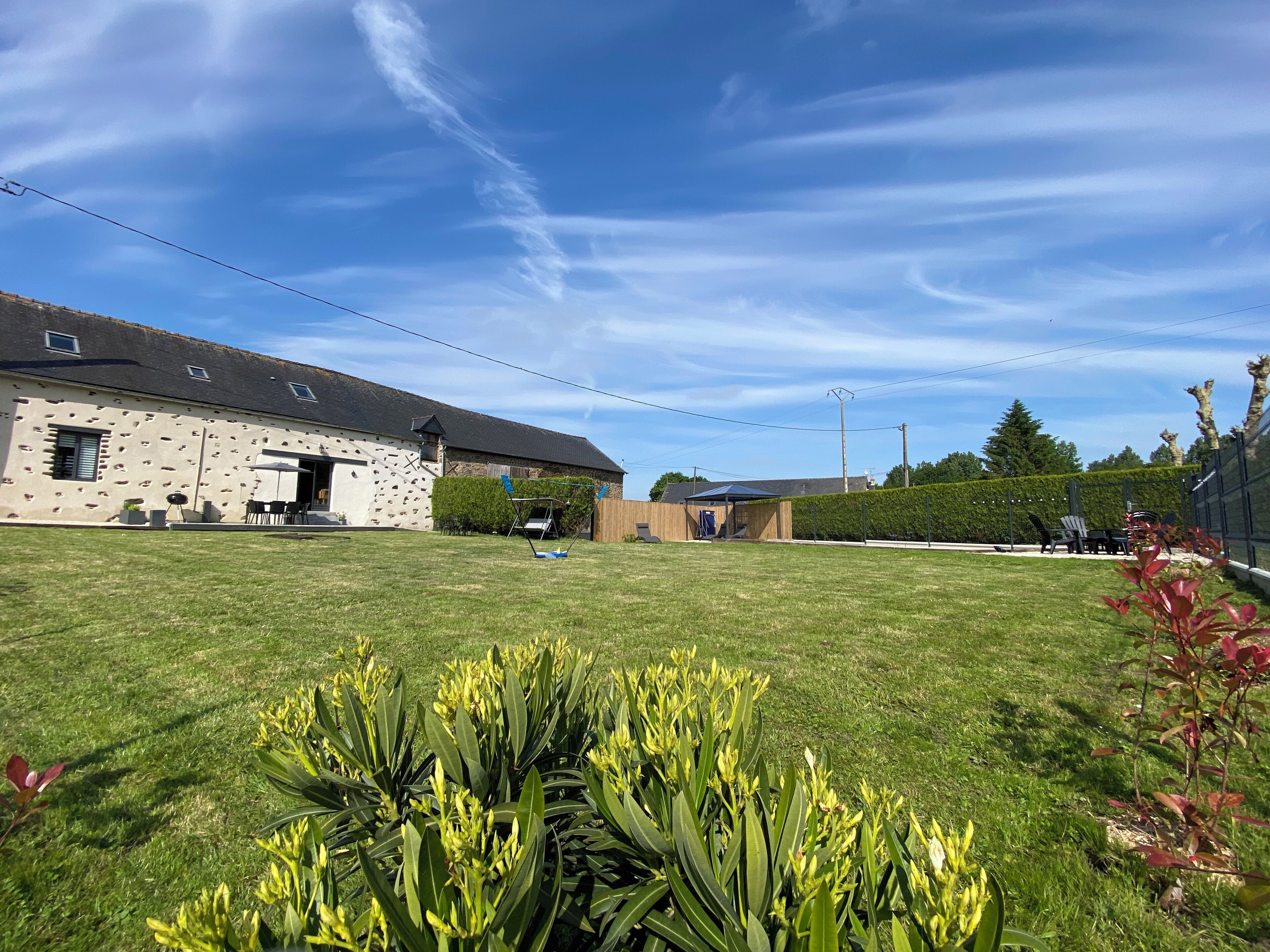 A building with a stone facade, a covered outdoor seating area, and a well-maintained lawn.