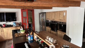 Eine moderne Küche mit Holzausstattung, einem Edelstahlkühlschrank und einem Essbereich mit Holztisch und Stühlen.