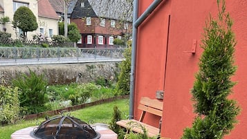 A garden area with a stone fire pit, a wooden bench, and a small tree.