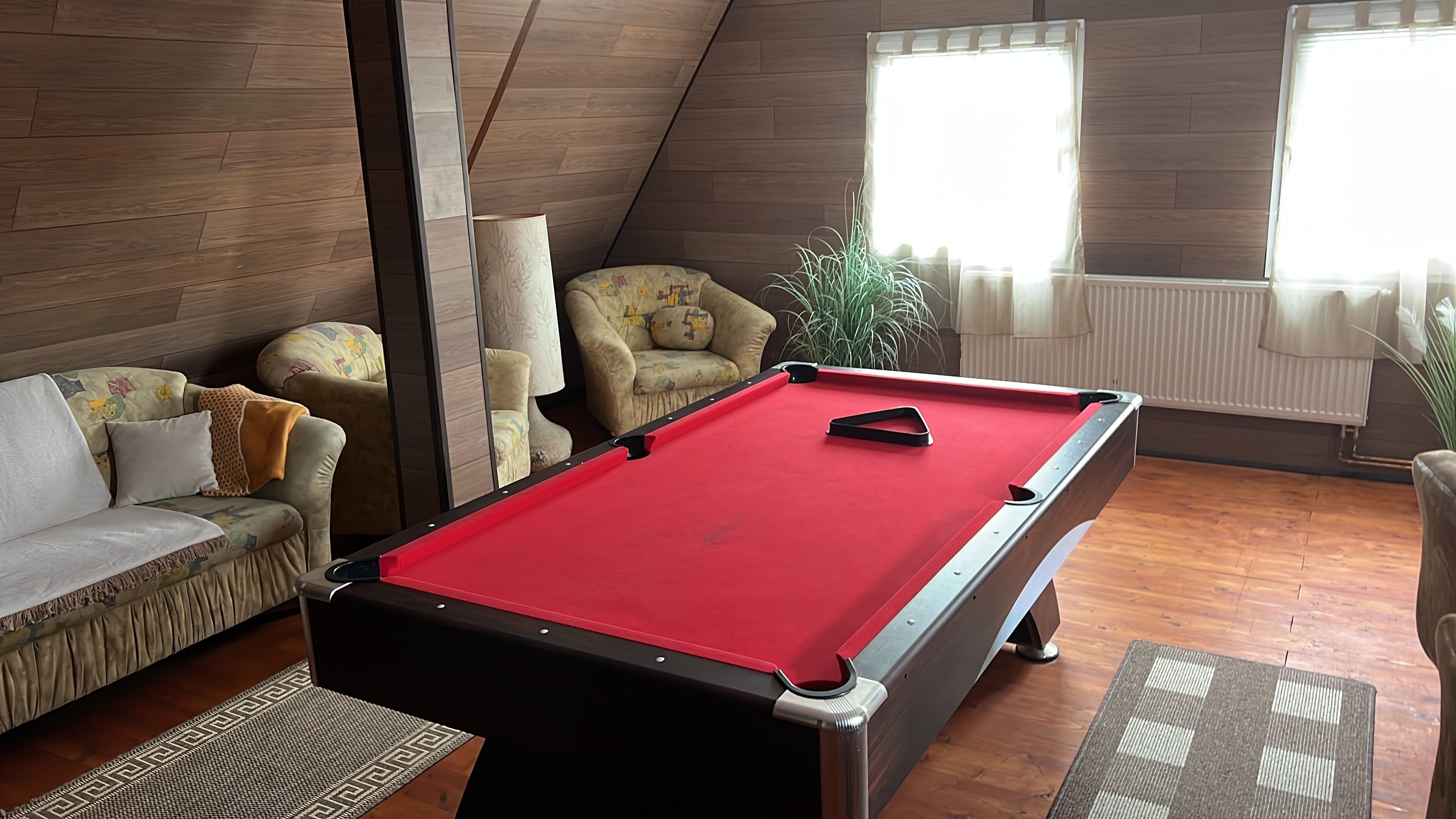 Une pièce confortable avec une table de billard, un canapé et un fauteuil.