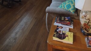 A living room with a sofa, a wooden coffee table with books, a rocking chair, and a dining table with chairs. There is a lamp on a side table and a painting on the wall. - Private 3-bedroom ranch, 10 miles from Bethany Beach, on a dead-end street. (Dagsboro)
