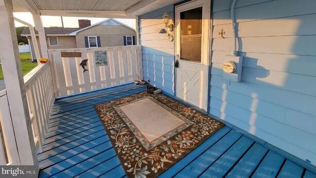 A covered porch with a blue floor, a white door, and a small window. - Private 3-bedroom ranch, 10 miles from Bethany Beach, on a dead-end street. (Dagsboro)