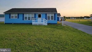 A single-story blue house with a front porch and a small deck. - Private 3-bedroom ranch, 10 miles from Bethany Beach, on a dead-end street. (Dagsboro)