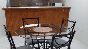 Una cocina con armarios de madera, una mesa redonda de vidrio y cuatro sillas.