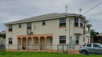 A two-story building with a flat roof, multiple windows, and a fenced front yard.
