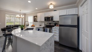 A modern kitchen with white cabinetry, stainless steel appliances, and a marble island. - Beautiful home in great location close to downtown, Nashville Heights (Nashville)
