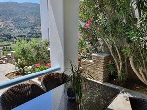 A balcony with wicker chairs, a table, and a potted plant. - Beautiful Elia apartment near the center of Andros - 5 minutes walk (Andros)