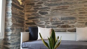 A room with a stone wall, a bed with a grey bedspread, and a potted plant. - Cozy Loft in Chora of Andros 1 min from the main beach! (Andros)