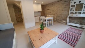 A modern living room with a wooden table, a potted plant, and a striped rug. - Cozy Loft in Chora of Andros 1 min from the main beach! (Andros)