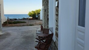 A stone building with a balcony overlooking a paved area and the sea. - Cozy Loft in Chora of Andros 1 min from the main beach! (Andros)
