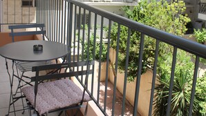 A balcony with a table and chairs, a railing, and a view of a multi-story building with balconies. - IQ Kleovoulou (Athens)