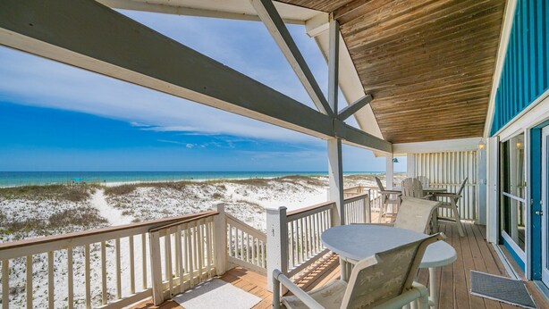 A wooden deck with a view of the beach and ocean.