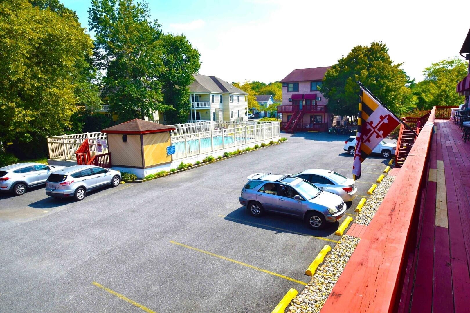 A parking lot with several cars, a small building with a red roof, and a flagpole with a flag.