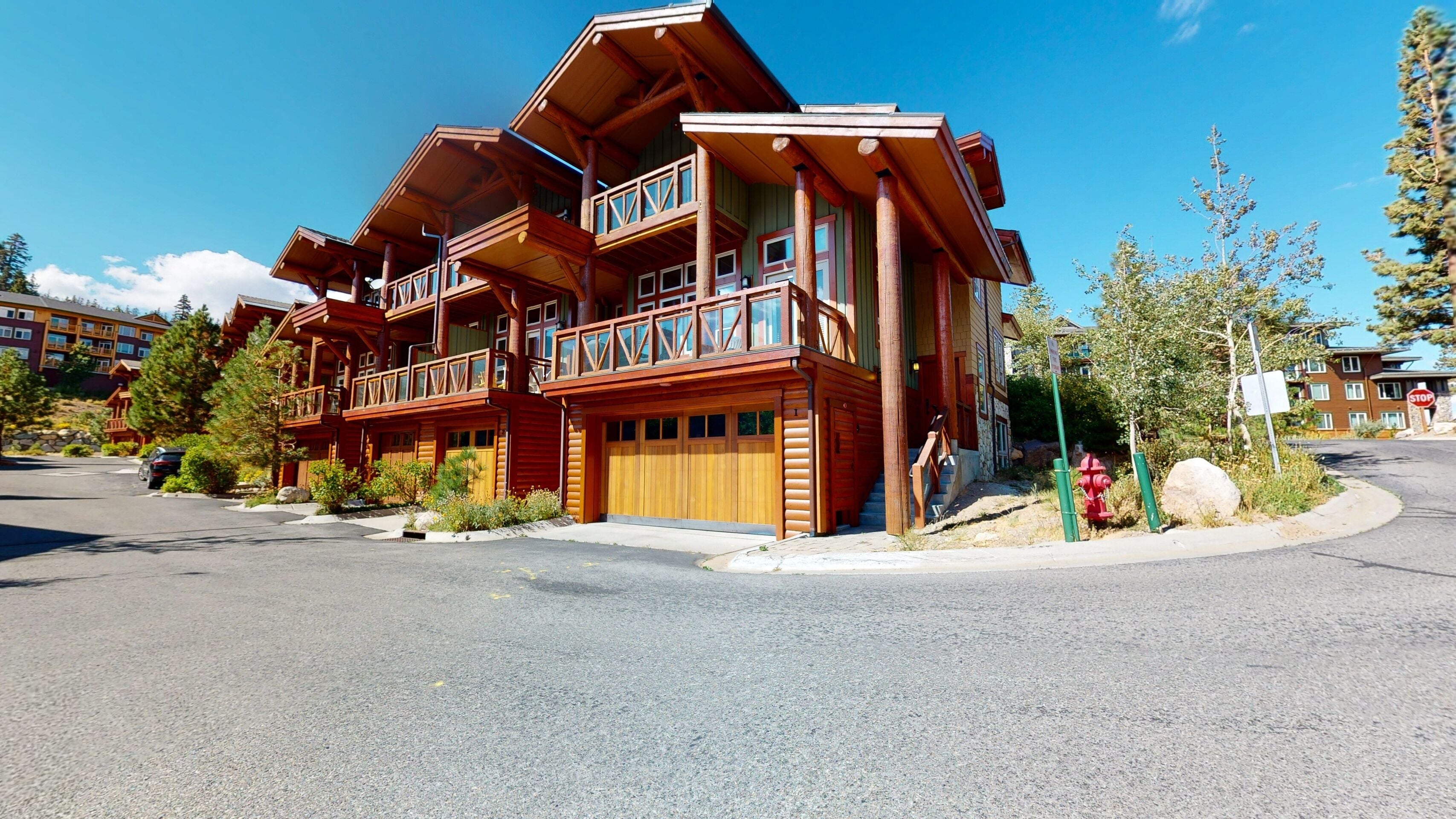 A multi-story log cabin-style building with a balcony, a garage, and a driveway.