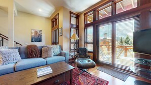 A living room with a sofa, a coffee table, a chair, and a television.