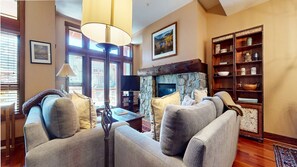 A cozy living room with a fireplace, comfortable seating, and a bookshelf.