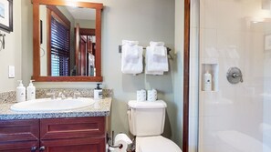 A bathroom with a sink, mirror, toilet, and shower.