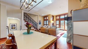 A spacious living room with a dining area, a staircase, and a stone accent wall. - Juniper Crest #2 3 Bedroom Townhouse by RedAwning (Mammoth Lakes)