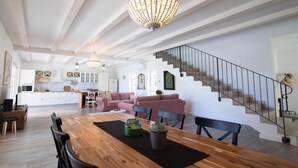 A spacious living area with a wooden dining table, a pink sofa, and a staircase with a metal railing. - Villa Stella Smoljanci (Svetvincenat)