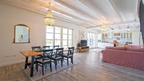 A spacious living area with a wooden dining table, multiple chairs, a pink sofa, and a kitchen in the background. - Villa Stella Smoljanci (Svetvincenat)