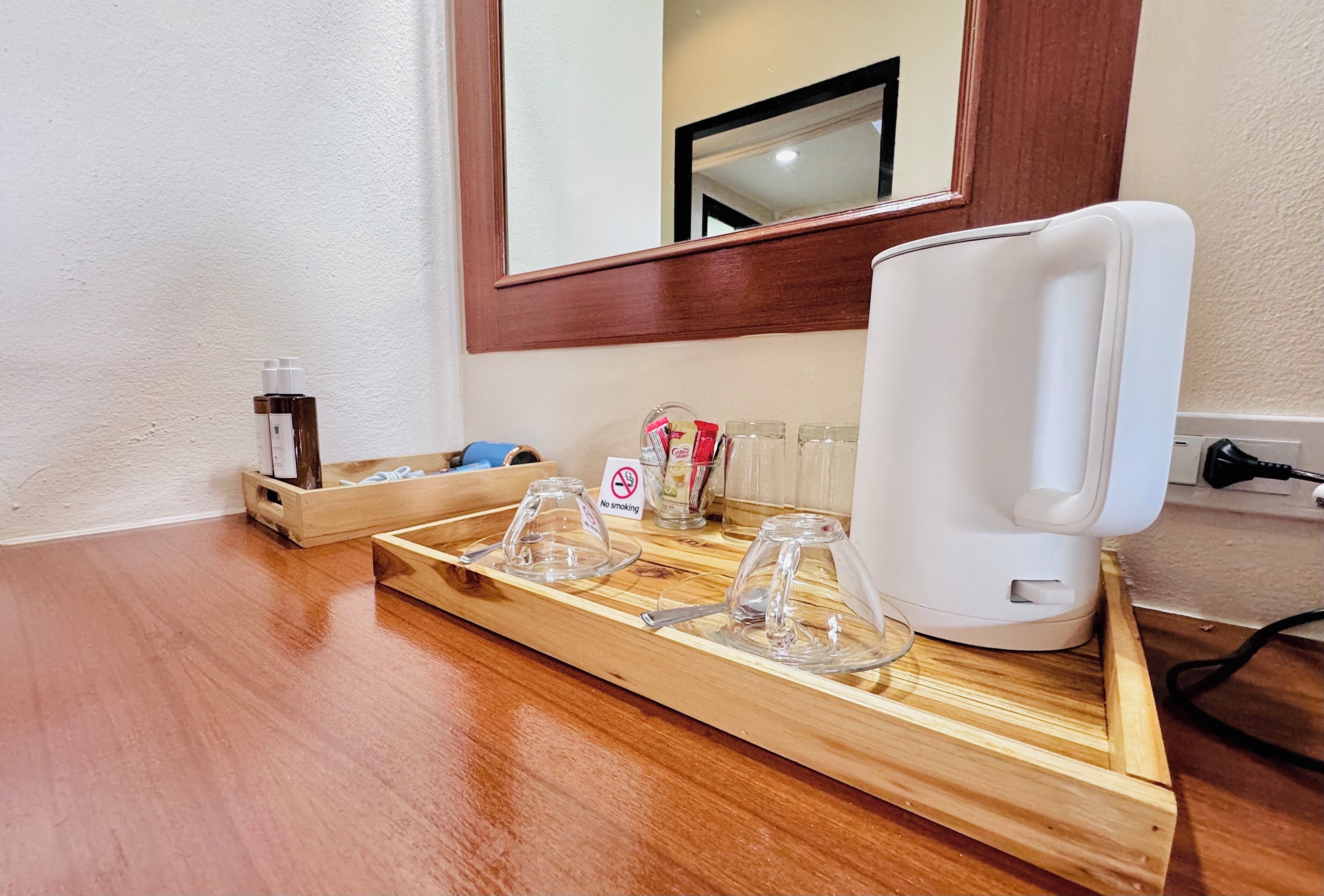 Un plateau en bois avec une cafetière blanche, un récipient en verre et un panneau « interdiction de fumer ».
