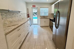 A modern kitchen with white cabinets, a stainless steel refrigerator, and a tiled backsplash. - 3/3 Duplex for 6+Shared Heated Pool, Tiki Bar BBQ (Hollywood)