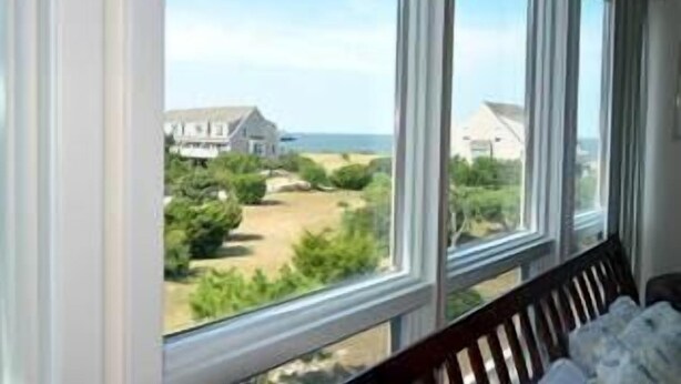 A room with a large window offering a view of a beach and houses. - Close to the beach with community pool! (Lewes)