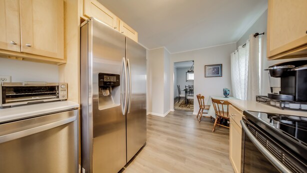 Una cocina moderna con electrodomésticos de acero inoxidable, armarios de madera y una zona de comedor con una mesa y sillas.