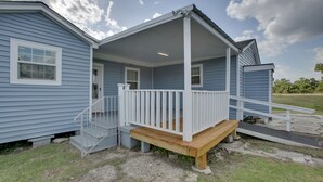 Ein blaues Haus mit Veranda, einer Holztreppe und einer kleinen Terrasse.