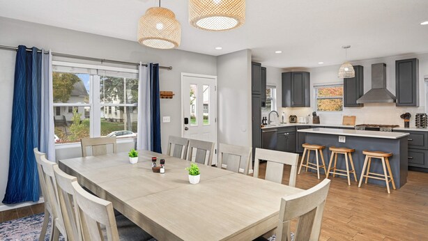 A modern kitchen with a central island, wooden chairs, and a dining table.