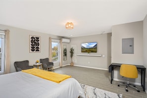 Une chambre d’hôtel moderne équipée d’un lit, d’un bureau, d’une chaise, d’une télévision et d’une fenêtre avec des rideaux.