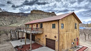 A wooden cabin with a red roof, a covered porch, and a garage. - Palisade Cottage on Orchard - Hike, Bike + More! (Palisade)