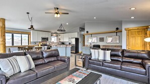 A spacious living area with leather sofas, a coffee table, and a kitchen in the background. - Palisade Cottage on Orchard - Hike, Bike + More! (Palisade)