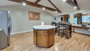 A kitchen with a central island, wooden ceiling beams, and a stainless steel refrigerator.