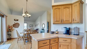 A kitchen with wooden cabinets, a central island, and a chandelier. - 5 Mi to Dtwn: Pet-friendly 'wheatland Twin' Home! (Fargo)