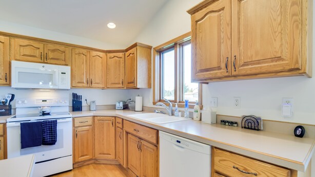 A modern kitchen with wooden cabinets, a white microwave, stove, and dishwasher. - 5 Mi to Dtwn: Pet-friendly 'wheatland Twin' Home! (Fargo)